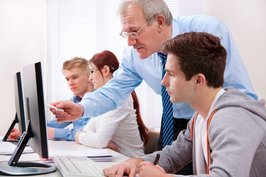 teacher assisting student on computer