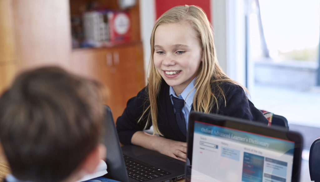 Two students working together in class while using a HP ProBook 11 EE and HP 240 G4.