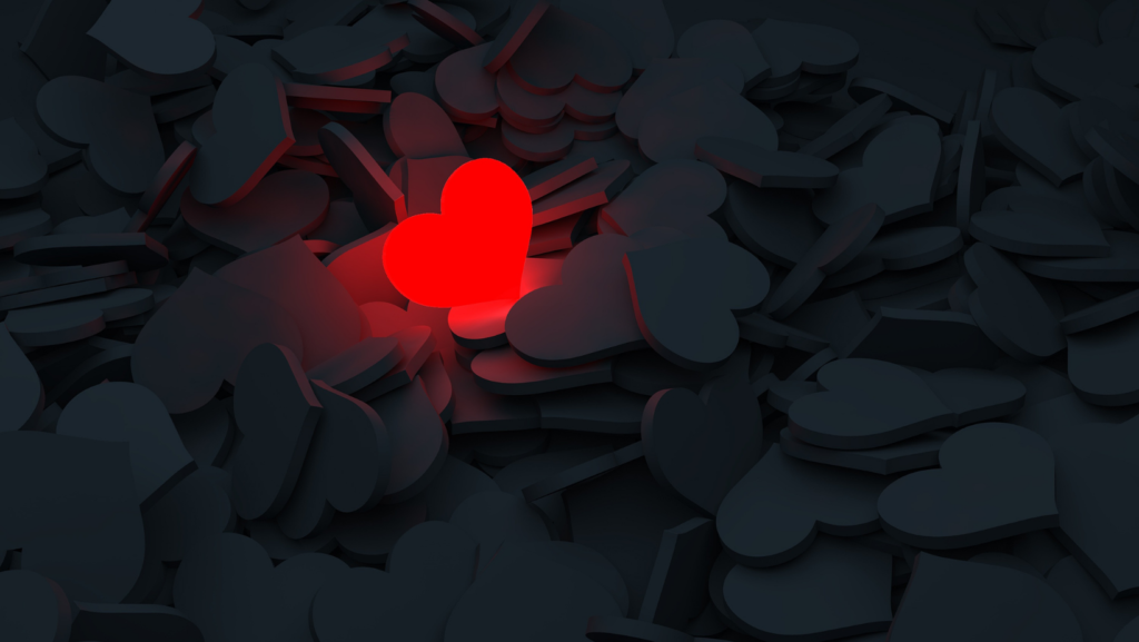 A lit up red heart in a sea of dark hearts