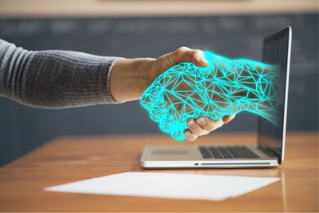 A hand reaching out to another through a laptop screen to offer support